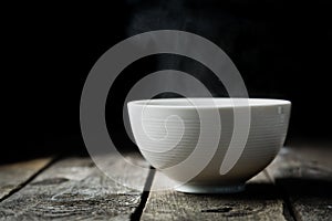 Steaming bowl on rustic wood background