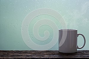 Steaming coffee cup on a rainy day window background