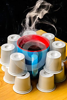 Steaming Coffee Cup surrounded by pods k cups on bamboo