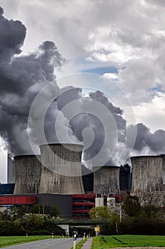 Steaming cooling towers of a power plant with dark gray emission