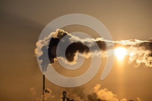 Steaming cooling towers and smoking industrial stacks against sunset gradient sky