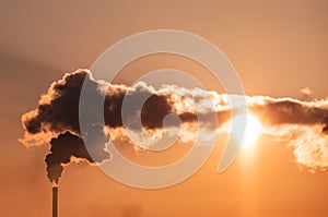 Steaming cooling towers and smoking industrial stacks against sunset gradient sky