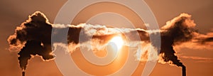 Steaming cooling towers and smoking industrial stacks against sunset gradient sky