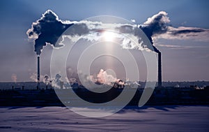 Steaming cooling towers and smoking industrial stacks against sunset gradient sky