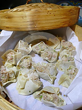 Steaming dim sum shumai in a bamboo basket