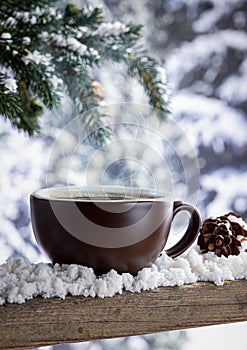 Steaming hot cup of coffee with winter background