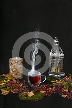 Steaming hot cup of tea with autumn background