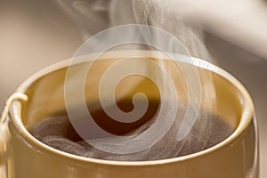 Steaming hot drink in ceramic cup close up