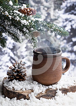 Steaming hot drink in a cup outdoors with snowy forest background