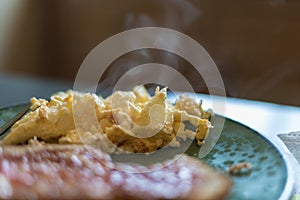 Steaming hot eggs on a green plate with toast blurry in the fore