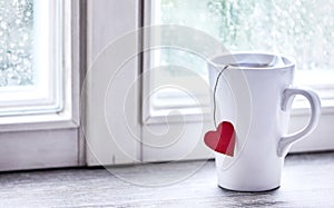 Steaming love heart morning tea mug on window sill