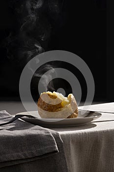 Steaming roasted potato on a plate with contrast backlight