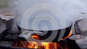 Steaming Skillet on a Blazing Bonfire in the Woods. Close up