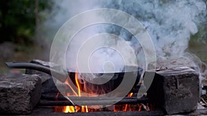 Steaming Skillet on a Blazing Bonfire in the Woods. Close up