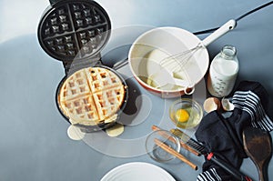 Steaming waffle iron making waffle, bowl of batter