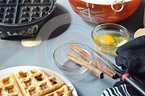 Steaming waffle iron making waffle, bowl of batter