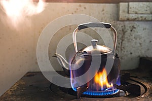 Steaming water in Traditional metal kettle on fire on gas stove