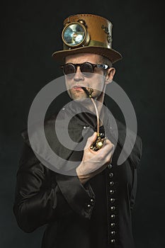 Steampunk man in a hat smoking a pipe.