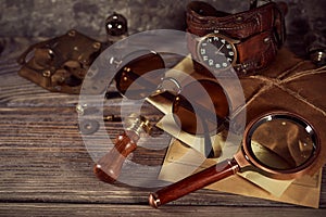 Steampunk still life - old vintage objects on a wooden background. Leather wrist watch, dark glasses, old tube lamps, magnifying g