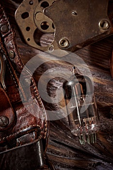 Steampunk still life - old vintage objects on a wooden background. Leather wrist watch, dark glasses, old tube lamps, magnifying g