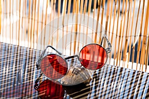 Steampunk Sunglasses with red lens placed on a shell shoot at summer in a very sunny day