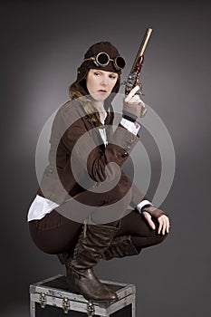 Steampunk woman wearing brown with aviator hat and gun