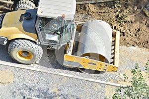 Steamroller performing leveling work on a road under construction. Equipment for construction and repair roads. Yellow steamroller