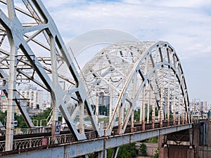 Steel arch trusses of the railroad bridge against city buildings