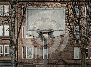 Steel basketball backboard with the hoop metal ring and steel chain net at outdoor basketball courts with old buildings background