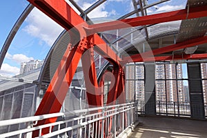 Steel beams in red against a blue sky. Overhead passage. Industrial background