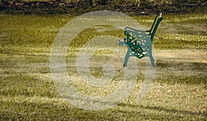 A steel bench in a green grass field. Empty chair in a park