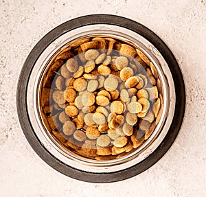 Steel bowl full of dog food on marble background flat lay top view