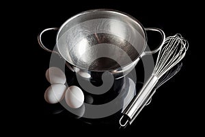 Steel bowl whisker eggs high angle with reflection on black