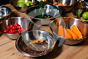 Steel bowls with raw ingredients for cooking at a culinary master class, bowl with cherry tomatoes, peeled carrots, cinnamon