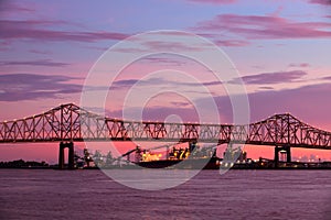 Steel bridge over Mississippi river under a stunning sunset sky in Baton-Rouge, Louisiana, with freight vessel and plant in the ba photo