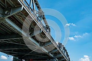 Steel bridge structure against blue sky and white clouds. Iron bridge engineering construction. Strong and strength metal bridge.