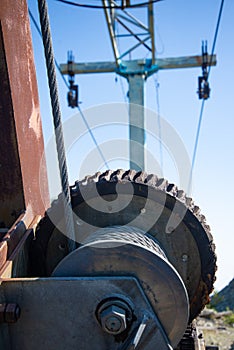 Steel cable and winch. Part of an old winch with a steel rope on a lift. Detail of the cableway. Close-up view of steel big wheel