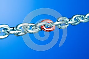 Steel chain with red link on blue background.