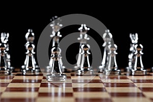 Steel chess figures standing on wooden chessboard