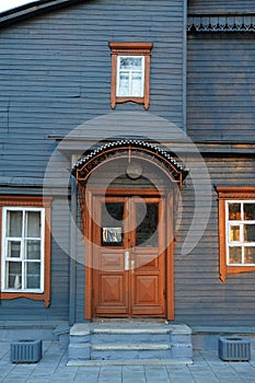 Steel colored wooden house facade with brown closed door and win