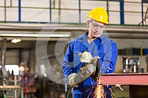 Steel construction worker cutting metal with angle grinder