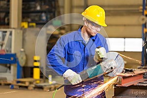 Steel construction worker cutting metal with angle grinder