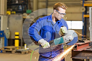 Steel construction worker cutting metal with angle grinder