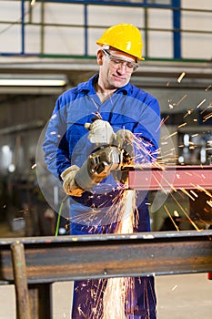 Steel construction worker cutting metal with angle grinder