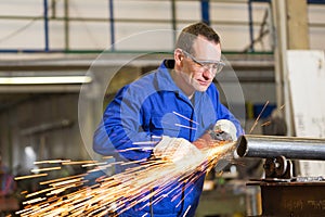 Steel construction worker grinding metal with angle grinder