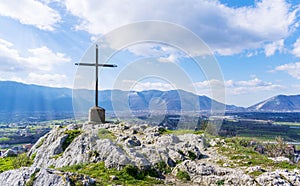 A steel cross on top hill of the mountain and rays of the sun on a blue skies background.