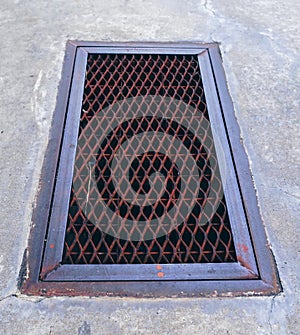 The steel drain grate cover is closed on the cement walkway