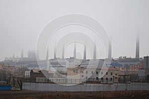 Steel factory with chimneys in fog
