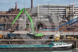 Steel factory in Dutch harbor IJmuiden with crane unloading barge