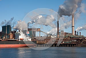 Steel factory with smokestacks and cargo ship